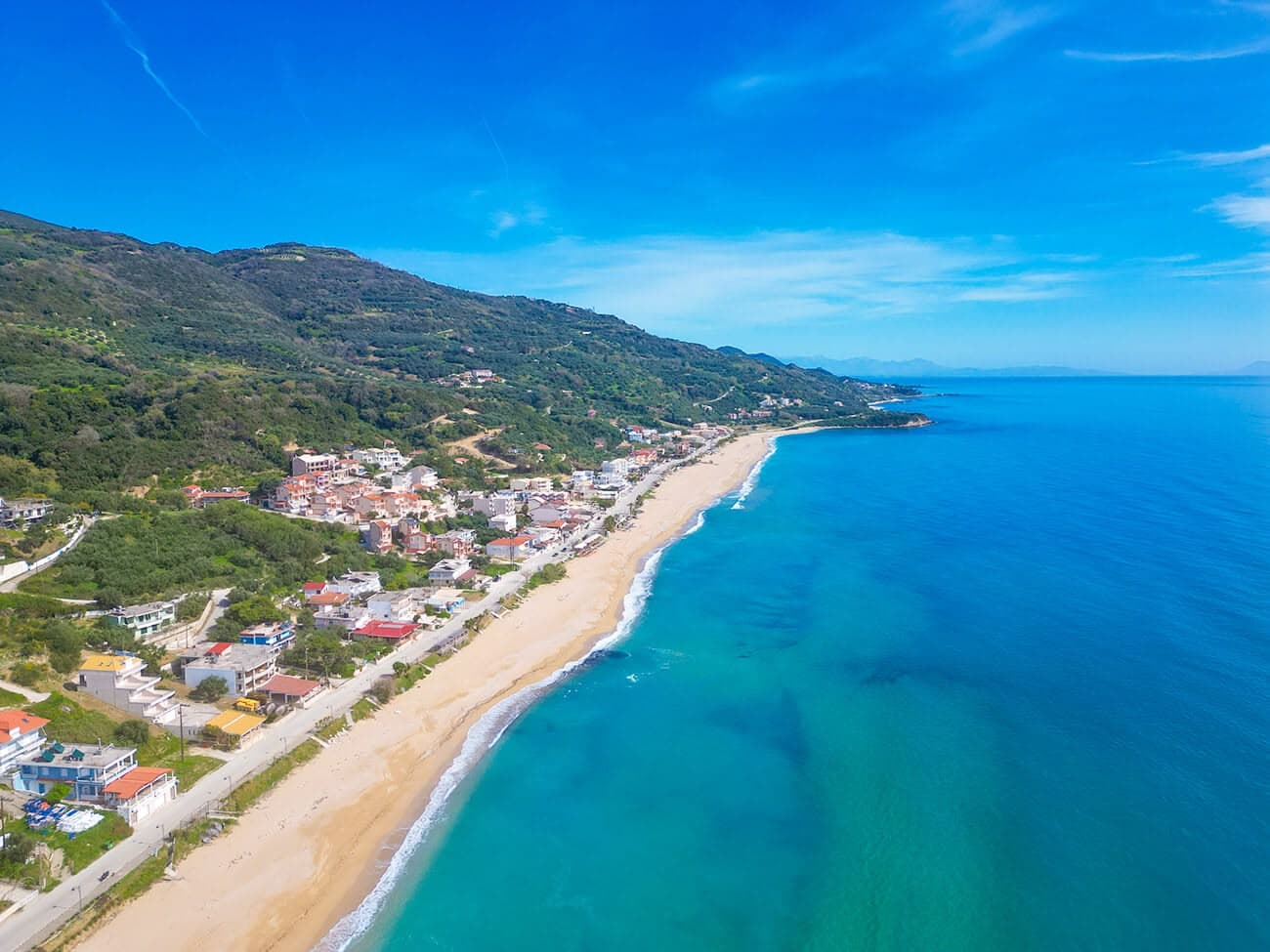 Loutsa beach with crystal-clear turquoise waters and golden sand under the Greek sun